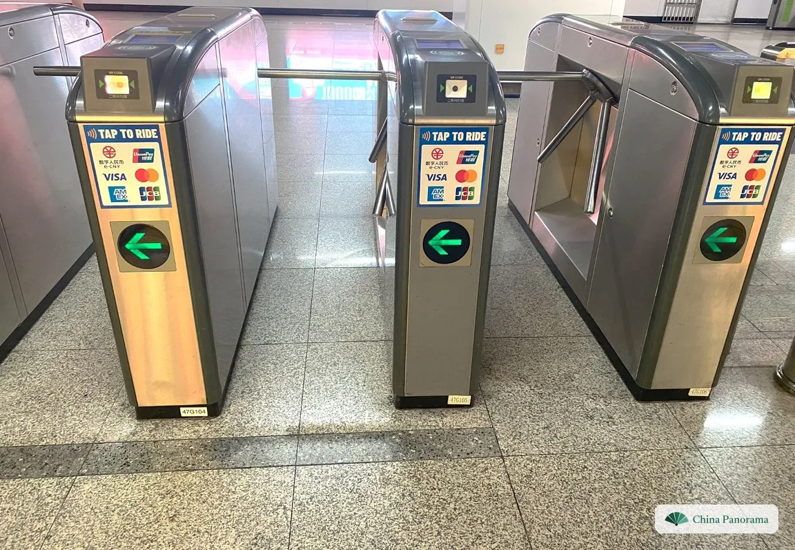 Metro gates with the Tap to Ride sticker and the logos of e-CNY, UnionPay, Visa, Mastercard, American Express and JCB, with green arrows below