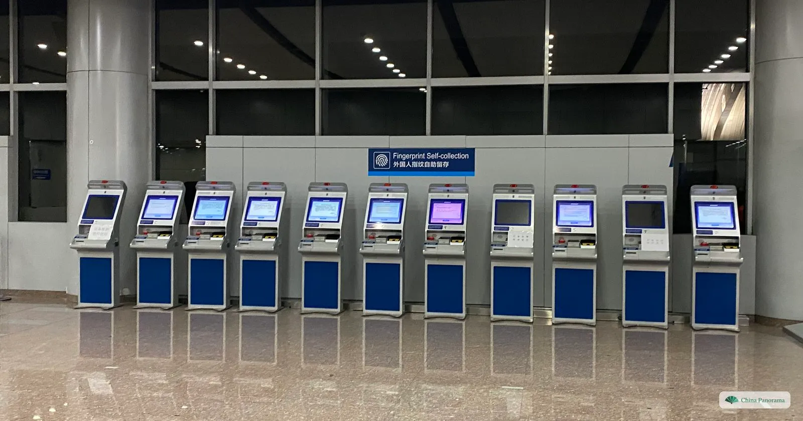 A row of eleven self-service kiosks under a sign reading Fingerprint Self-collection