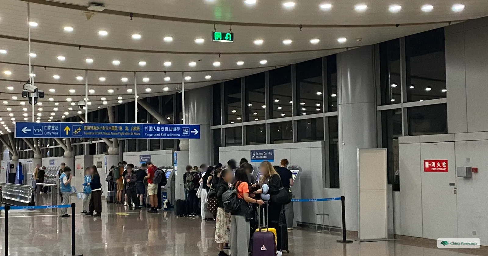 Arrival hall at Beijing airport with signs for Entry Visa, 24-hour transit and fingerprint self-collection, and travellers queuing at kiosks under a sign reading The Arrival Card Filling