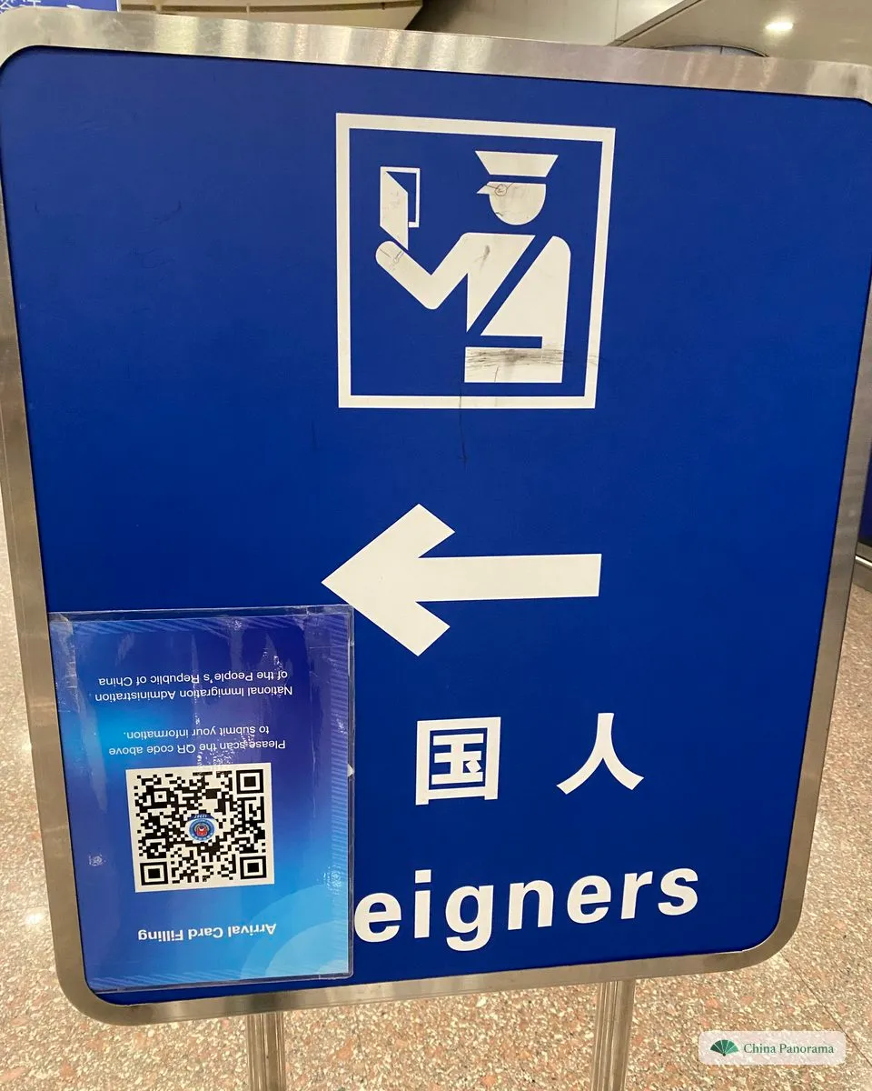 Blue sign for the foreigners’ immigration counters with an arrival card QR code card attached, mounted upside down