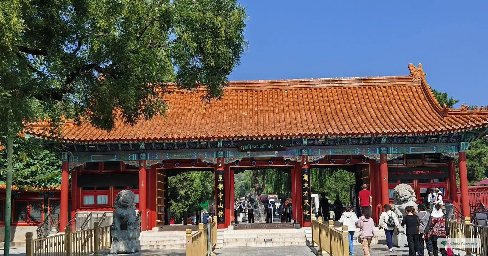 The main gate of Badachu Park, a red-columned gatehouse with an orange tiled roof and stone lions, with visitors going in