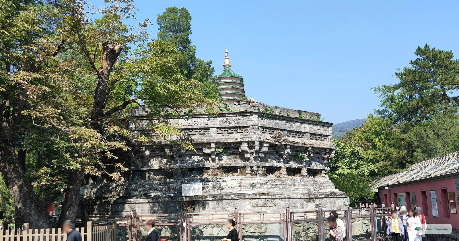 The weathered stone base of the ruined Zhaoxian Pagoda at Badachu, with carved brackets and niches, behind a fence