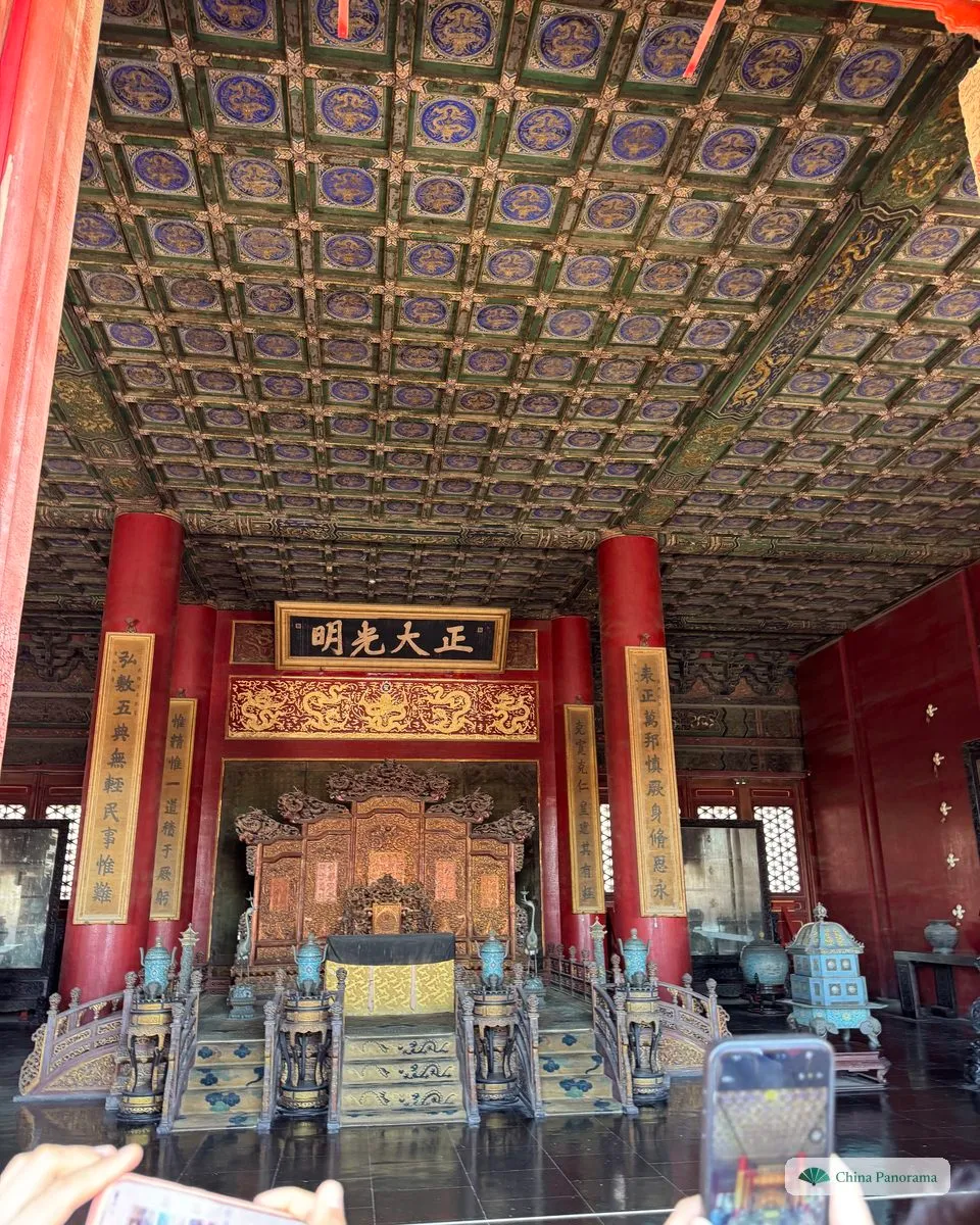 The throne of the Palace of Heavenly Purity seen from the doorway: a gilded screen and dais between red columns, a plaque with four gold characters above and a coffered ceiling of painted dragons