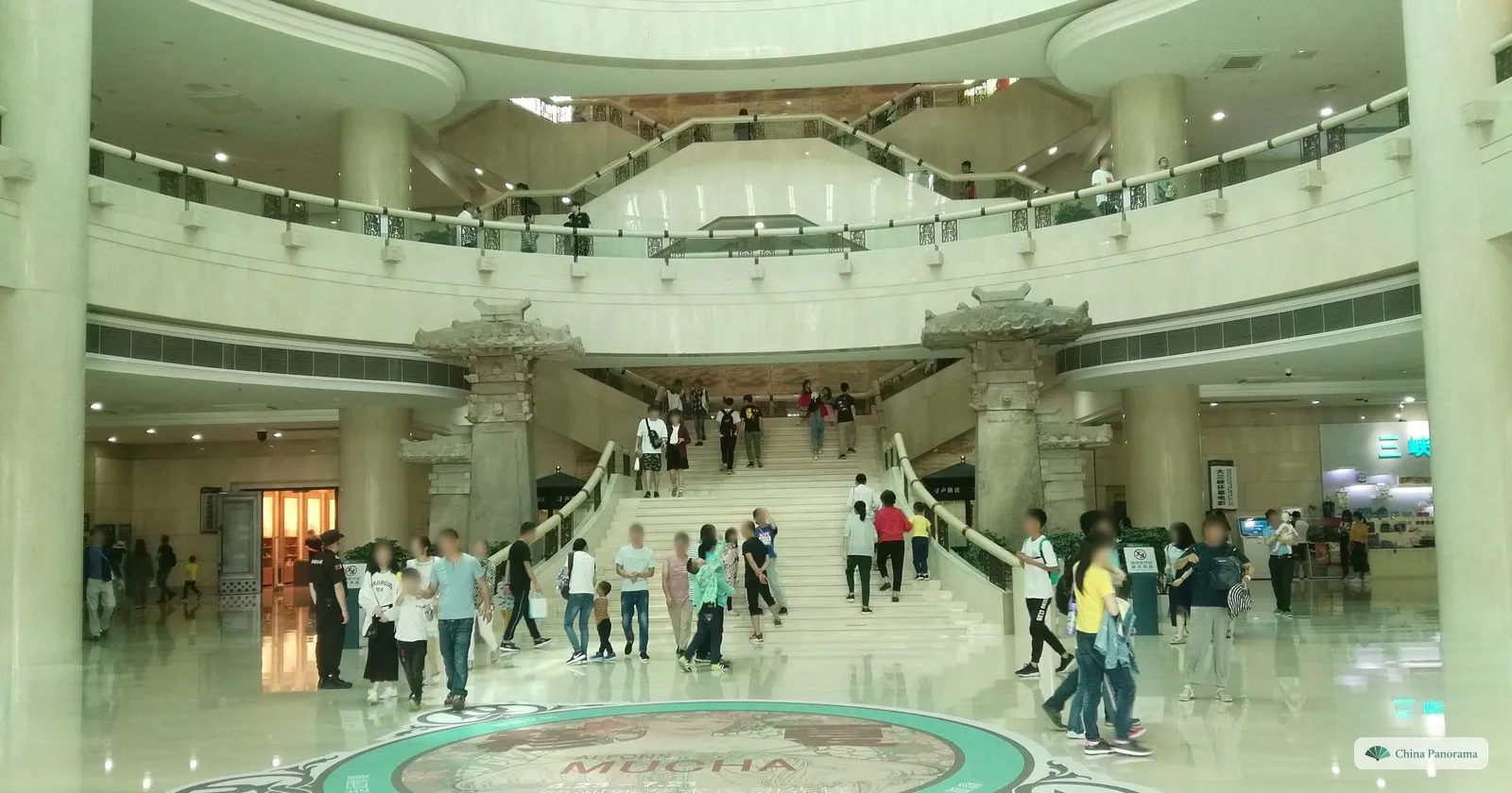 The entrance hall of the Three Gorges Museum: a wide marble staircase between stone pillars carved like Han-dynasty gate towers, visitors on the steps