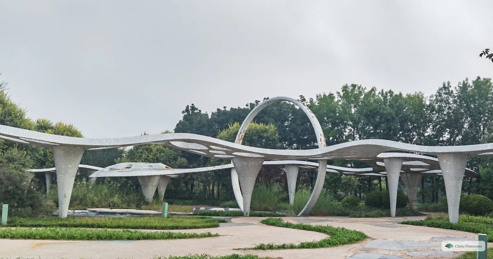 A white ribbon-like canopy on slender supports with a large ring, among lawns in Beijing Garden Expo Park