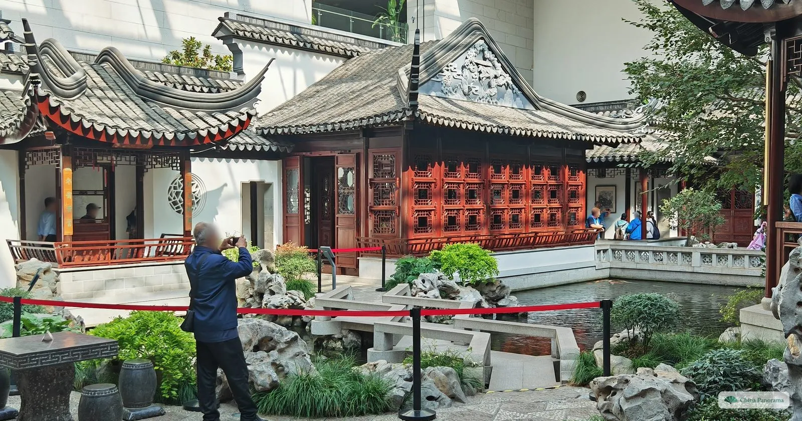 A Suzhou-style garden courtyard inside the Museum of Chinese Gardens, with a lattice-windowed hall, zigzag stone bridge and rocks