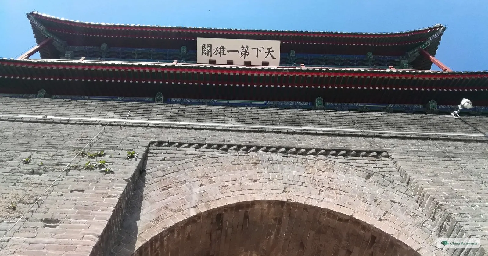 Looking up at the gate of Juyongguan: a stone arch and, under the eaves, a plaque reading 天下第一雄关