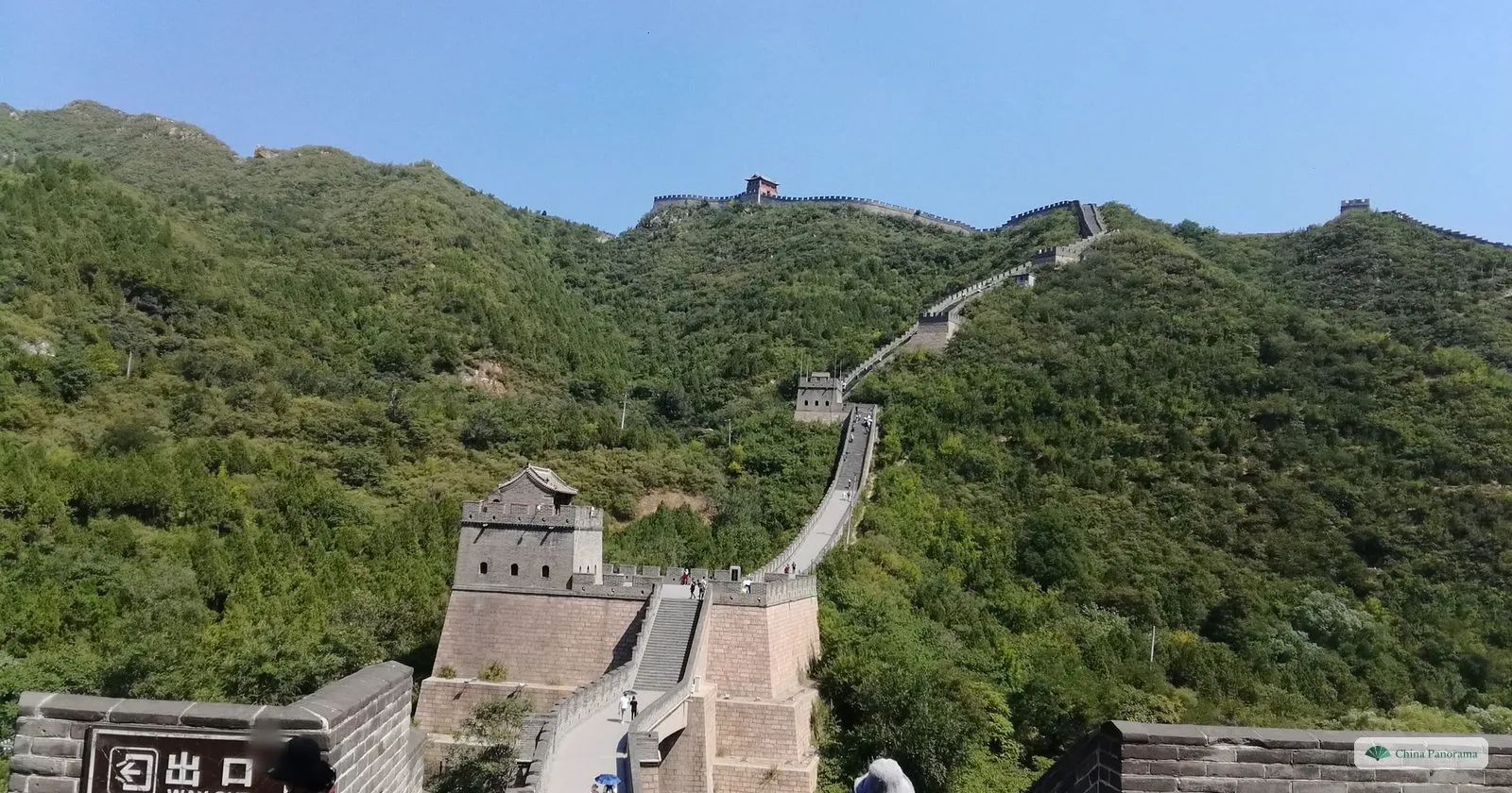 The Great Wall at Juyongguan climbing a steep wooded ridge in a zigzag, with a watchtower in the foreground