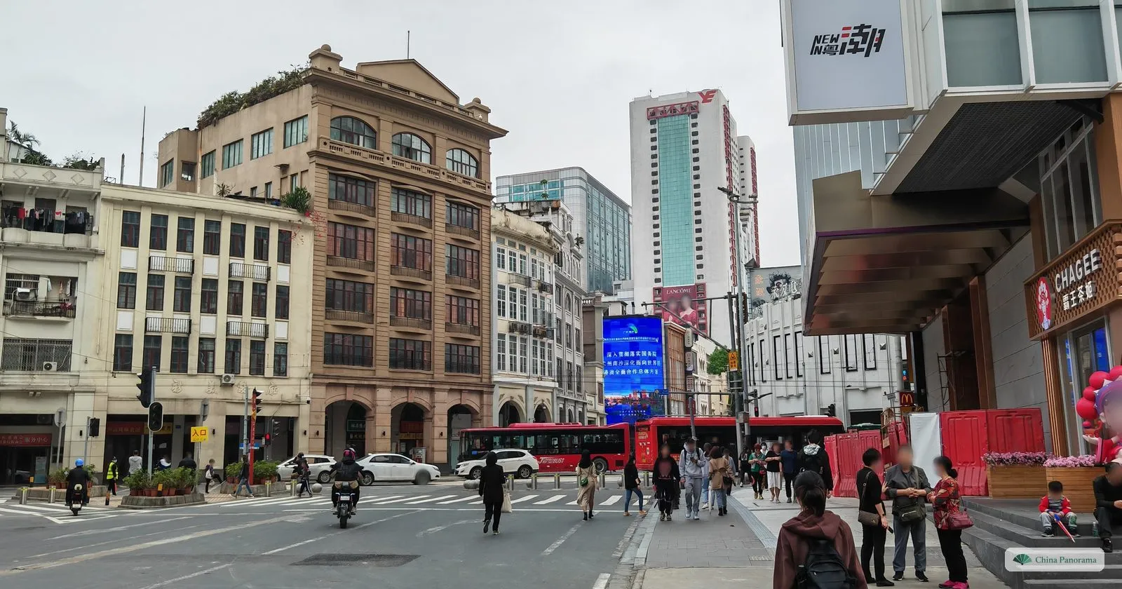 A junction at Beijing Road with early twentieth-century buildings across the street, red buses and pedestrians on the crossing