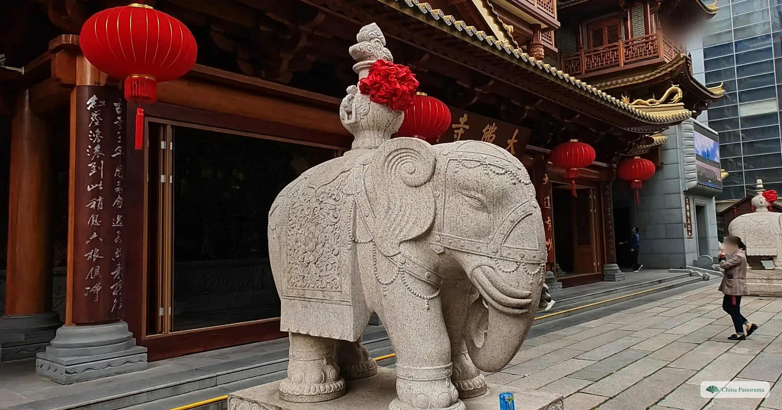 A carved granite elephant with a red silk flower on its head, standing at the foot of the steps of Dafo Temple