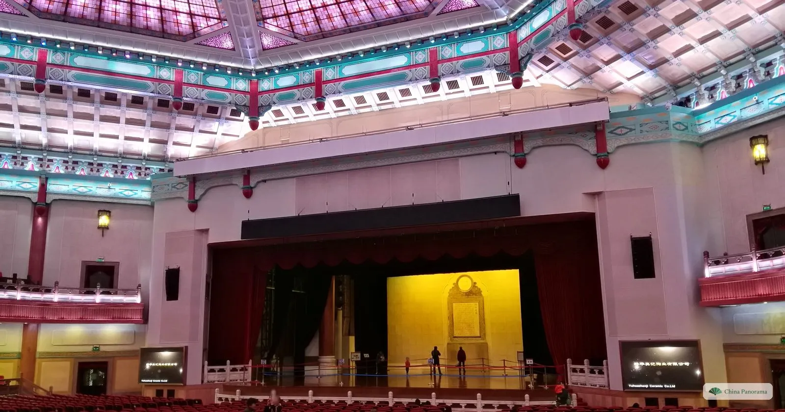 The auditorium of the Sun Yat-sen Memorial Hall: a large stage with red curtains and a gold backdrop, seen from the seats under a painted ceiling