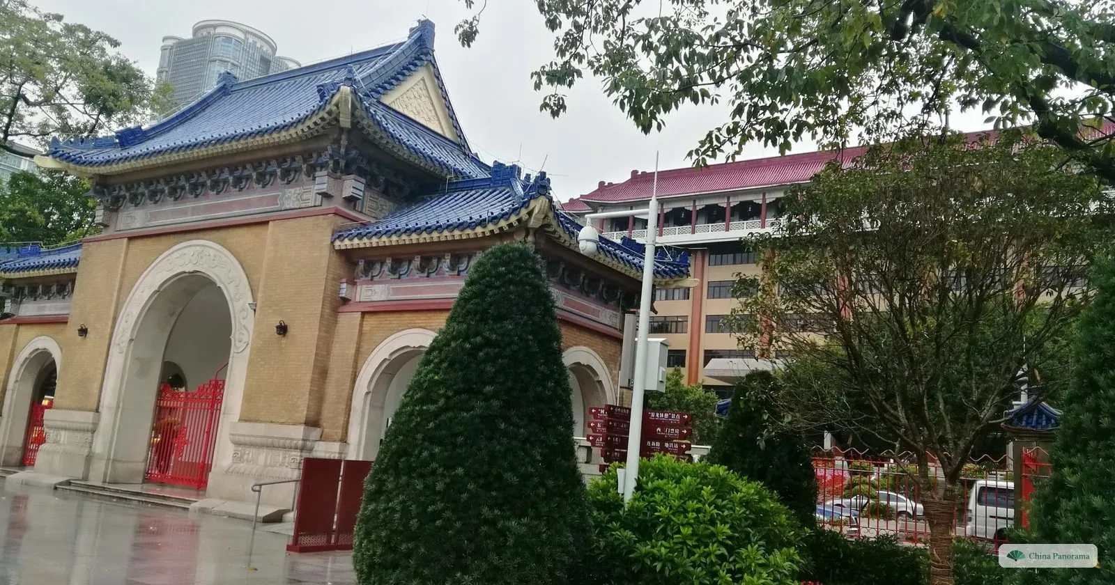 The south gate of the Sun Yat-sen Memorial Hall, a cream-coloured gatehouse with three arches under a blue-tiled roof, on a wet day