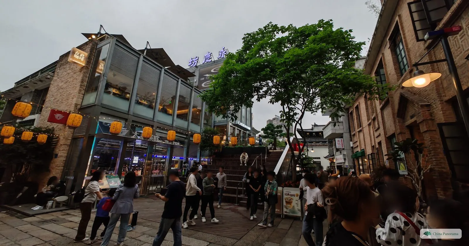 A paved square in Yongqingfang hung with orange lanterns, old brick buildings converted into cafés and a busy evening crowd
