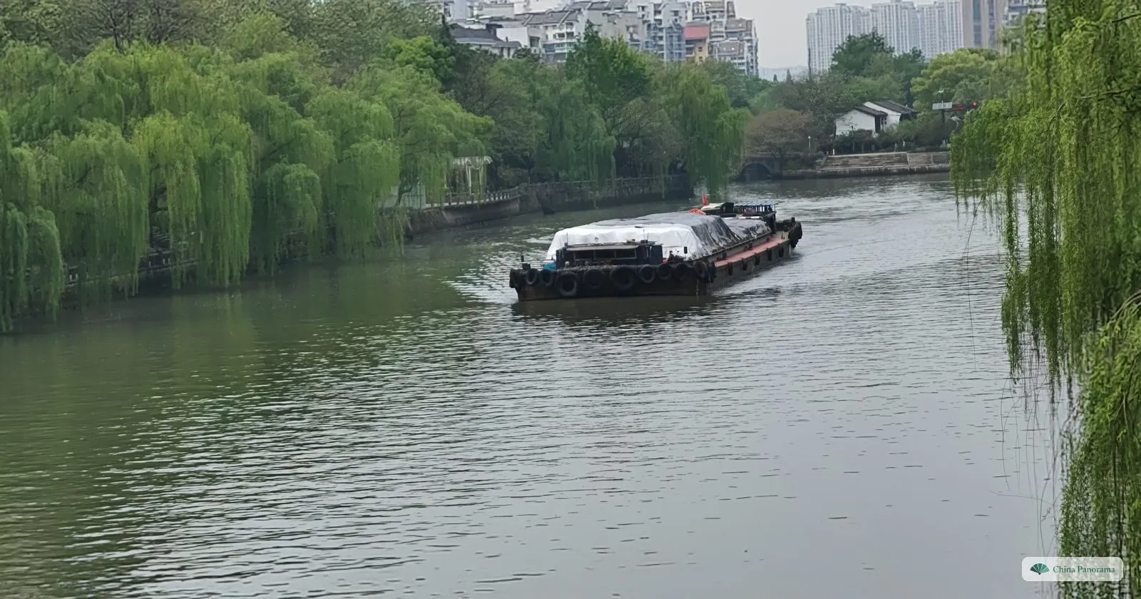 A cargo barge on the Grand Canal between banks of weeping willows