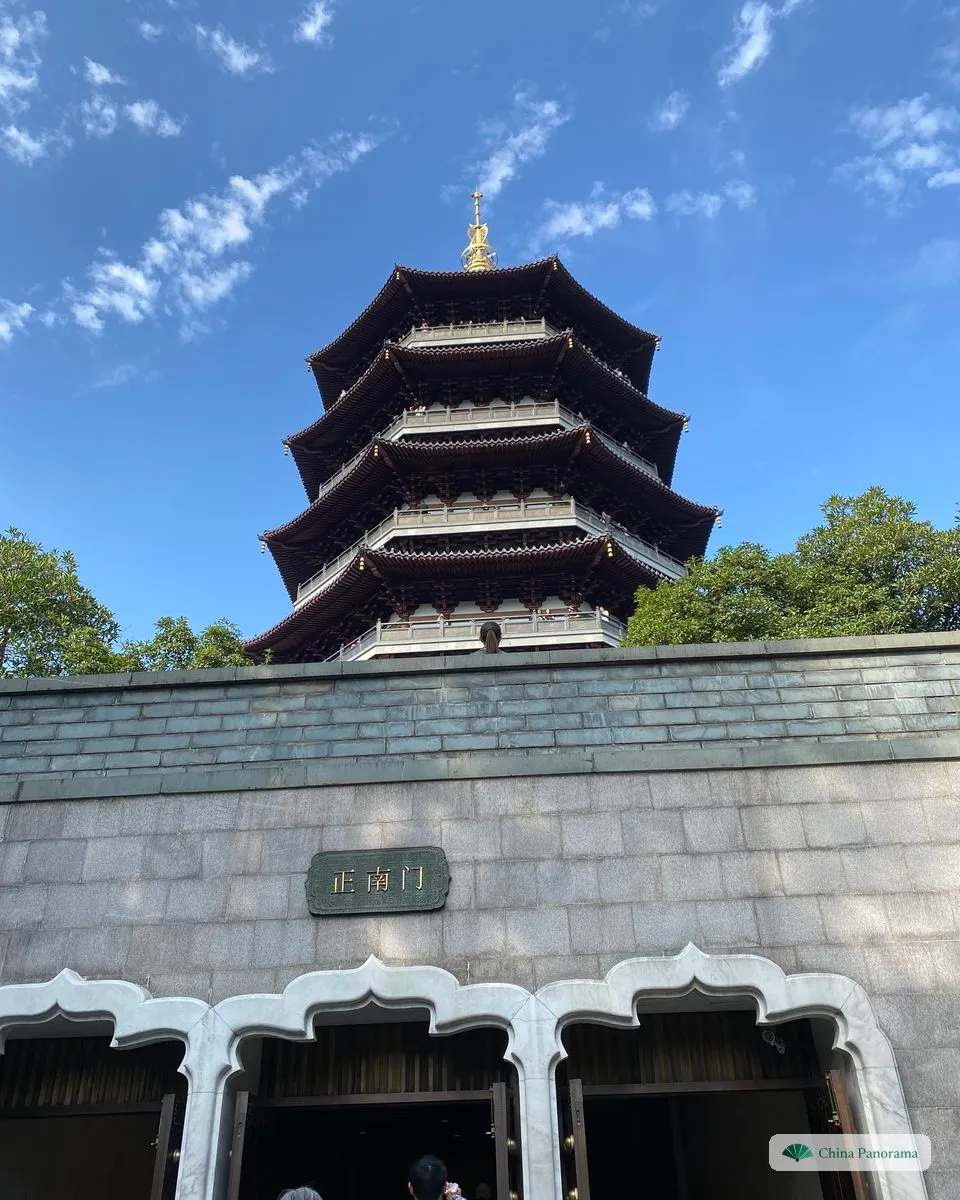 Looking up at an octagonal pagoda with five tiers of dark curved eaves and a golden spire against a blue sky