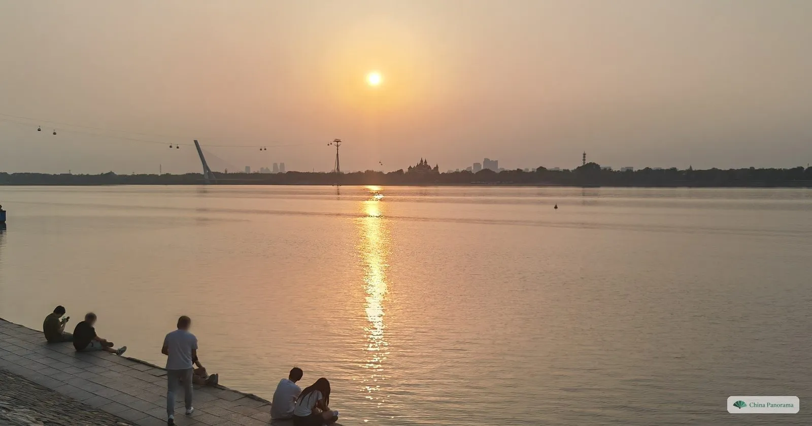 Sunset over the Songhua River in Harbin with people sitting on the embankment steps