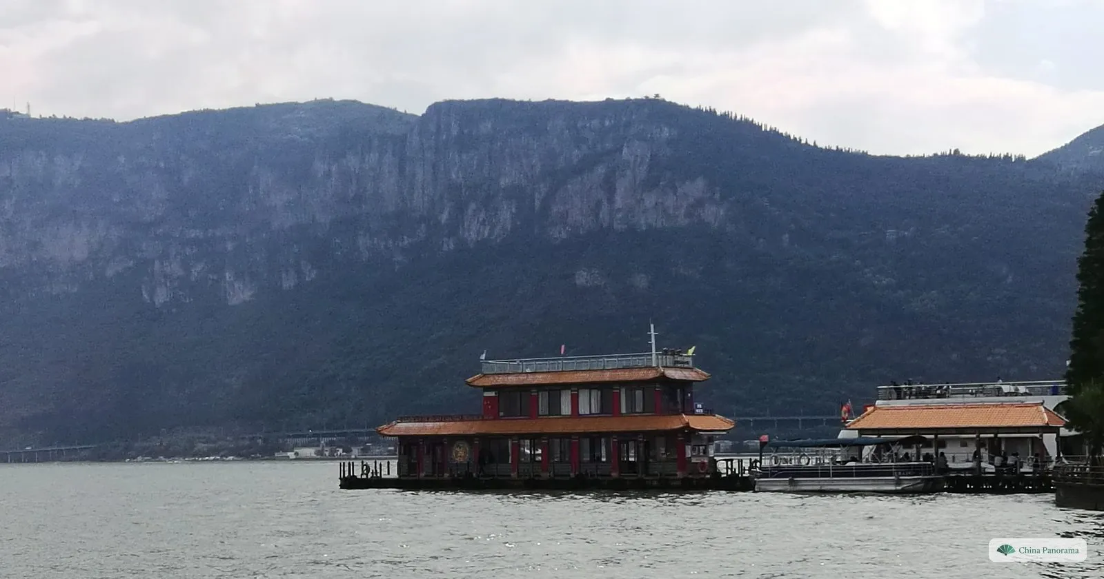 A floating restaurant on Lake Dianchi with the grey cliffs of the Western Hills behind