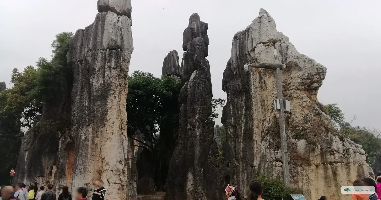 Three tall weathered rock pillars, one pale and cracked, with visitors at their feet