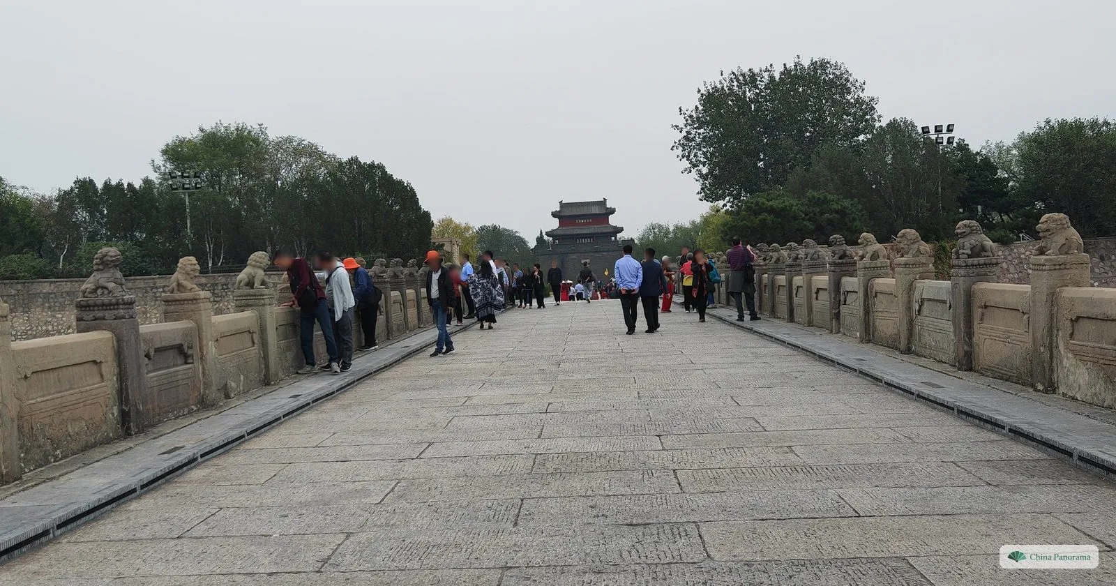 The deck of Lugou Bridge with its worn central paving stones and rows of stone lions on the parapets, looking towards the gate of Wanping