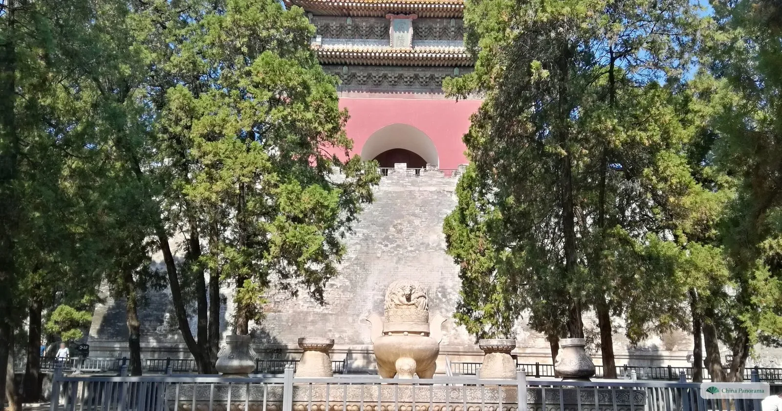 The soul tower of Dingling above its stone base, with a carved stone altar and incense burner in front, between tall cypresses
