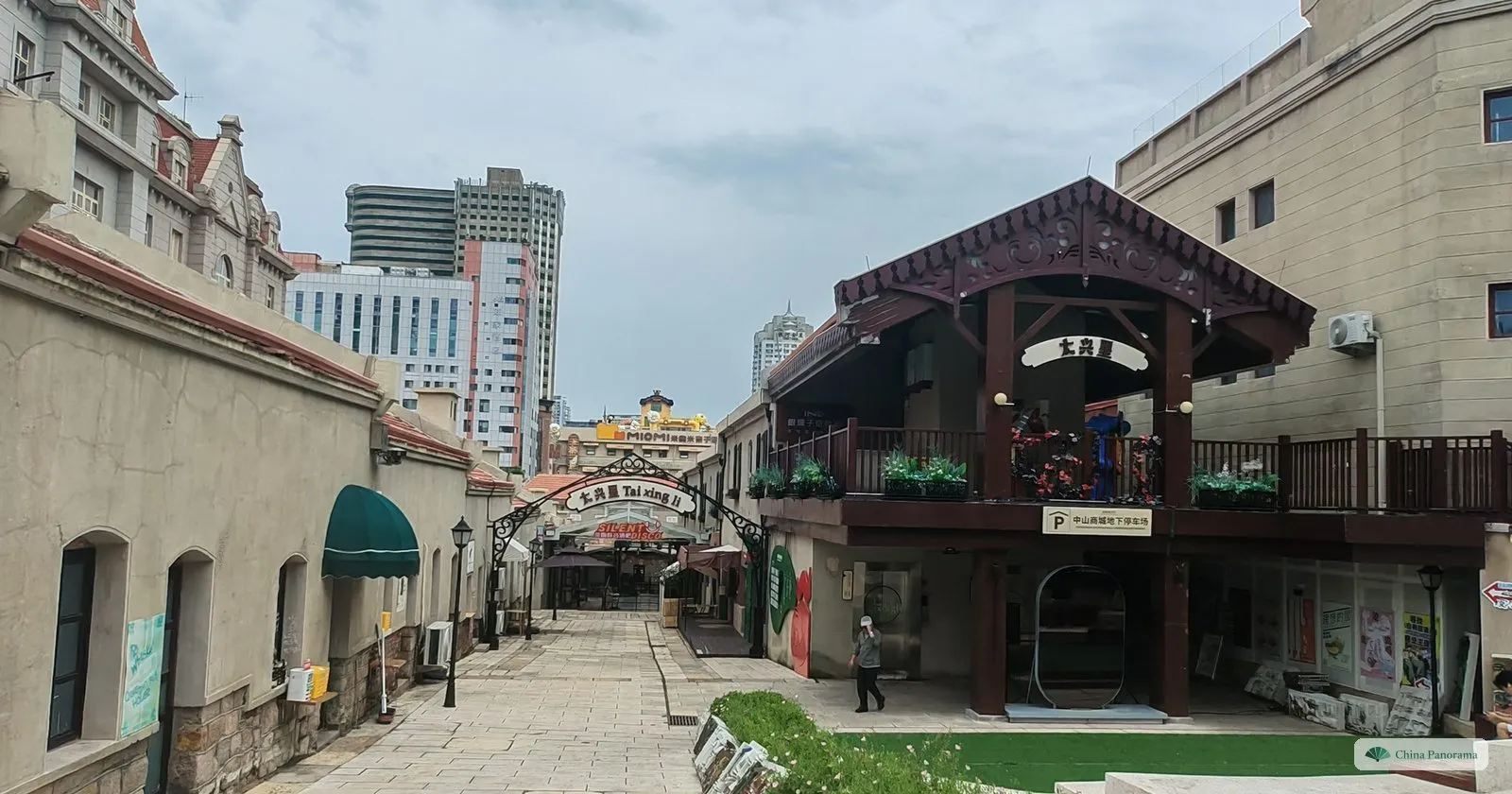 A restored lane in the Dabaodao quarter of Qingdao with a timber-balconied house and courtyard buildings