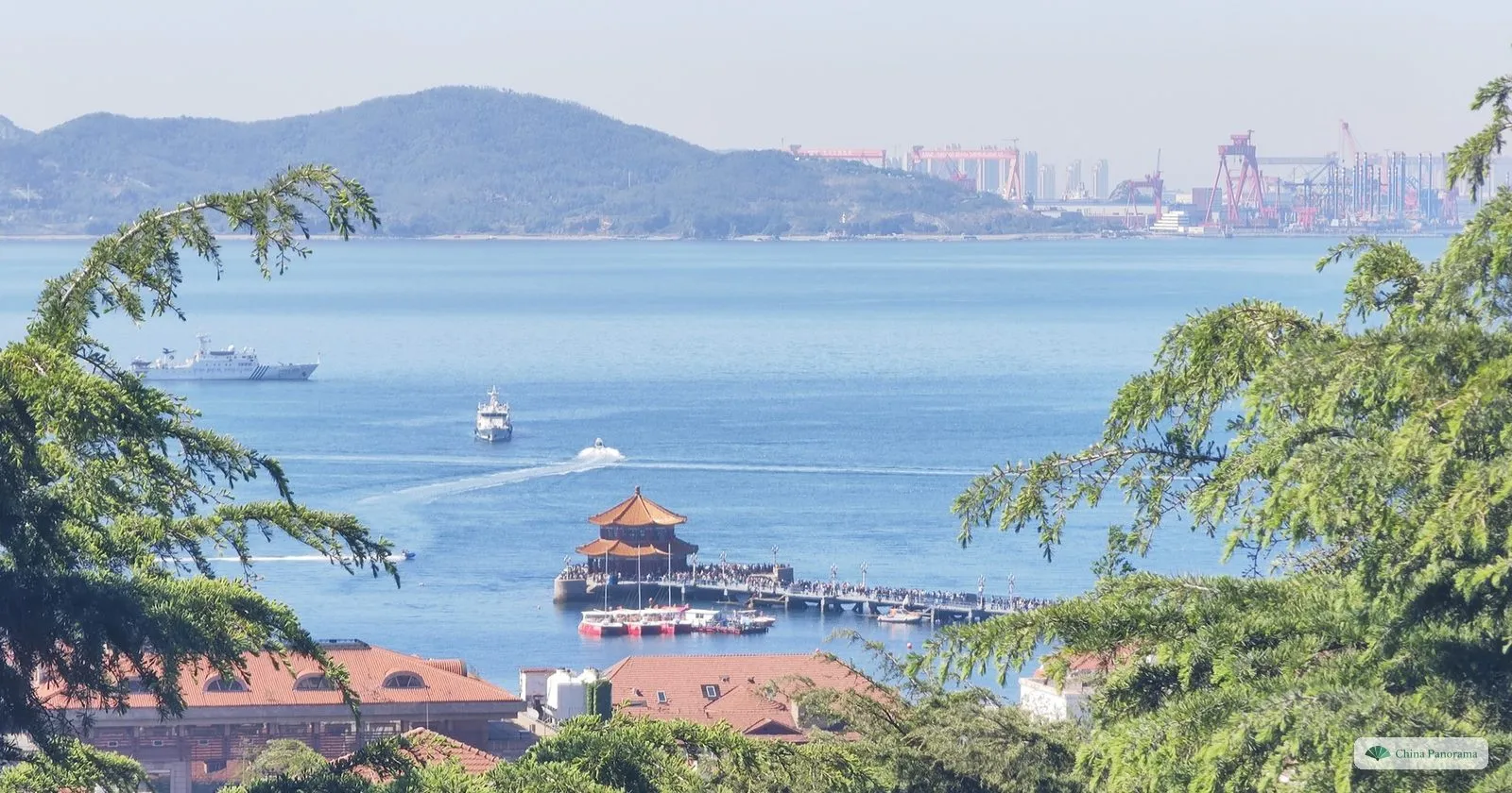 View from Guanhai Hill down to Zhanqiao Pier and the Huilan Pavilion, with boats in the bay and the West Coast hills behind