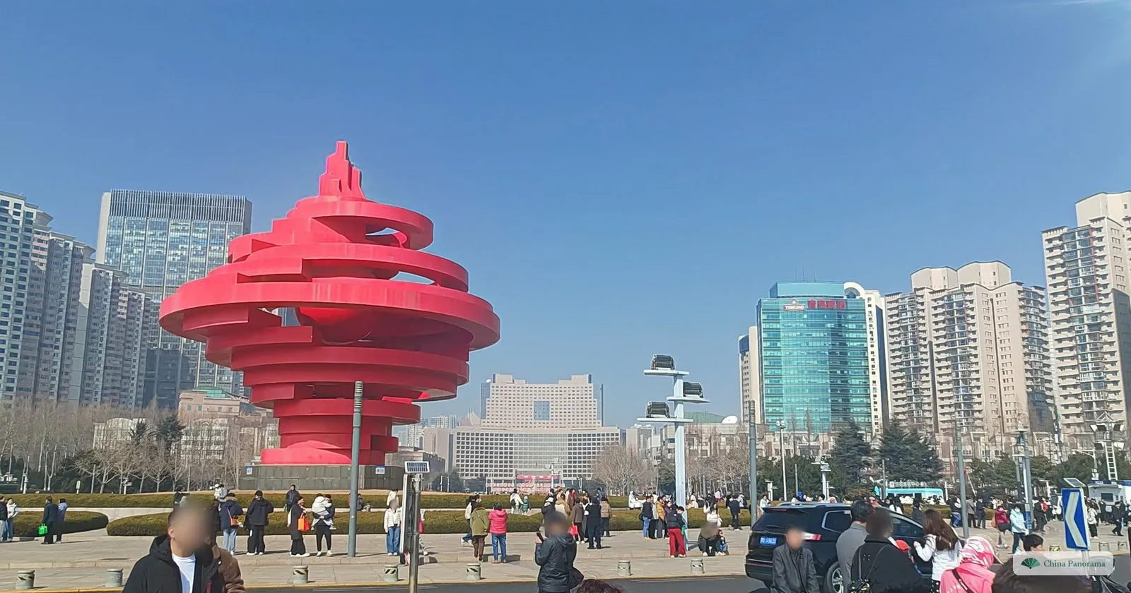 The red spiral “May Wind” sculpture on May Fourth Square in Qingdao, with high-rises behind