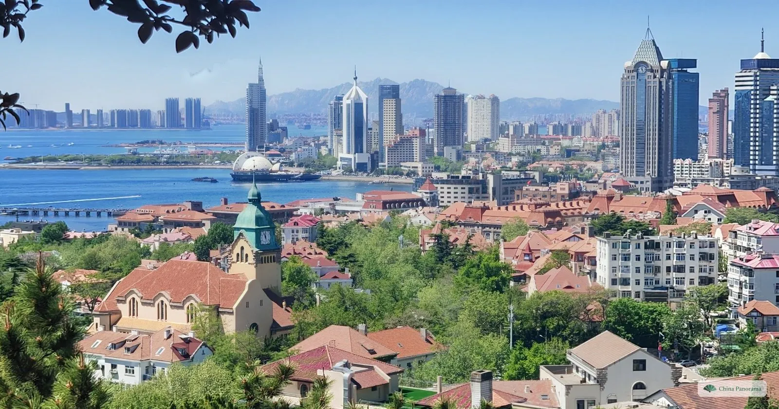 View from Signal Hill in Qingdao over red-tiled roofs and the green clock tower of the Protestant Church to the bay and the skyline