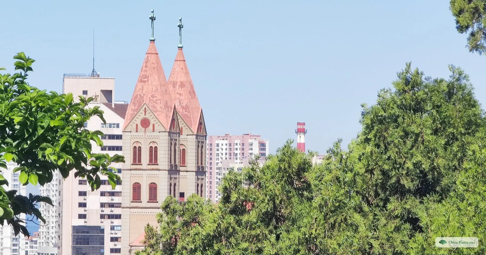 St. Michael’s Cathedral in Qingdao, a twin-spired Romanesque-revival church with red-tiled spires, seen through trees