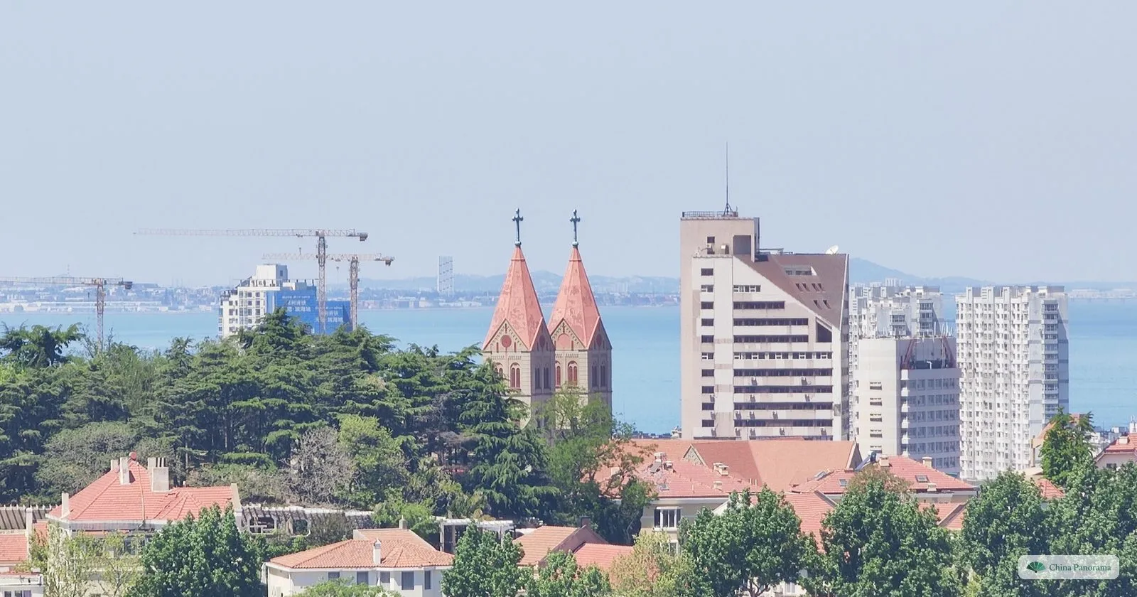 The twin spires of St. Michael’s Cathedral rising above the old-town roofs of Qingdao, seen from Signal Hill