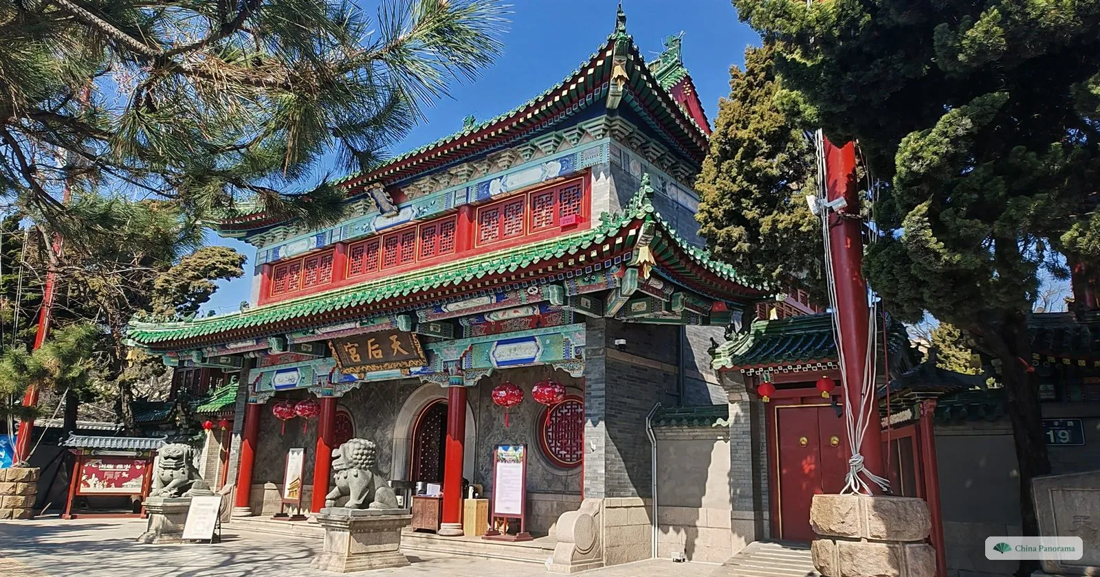 The painted gate hall of Tianhou Temple in Qingdao, with stone lions and pine trees