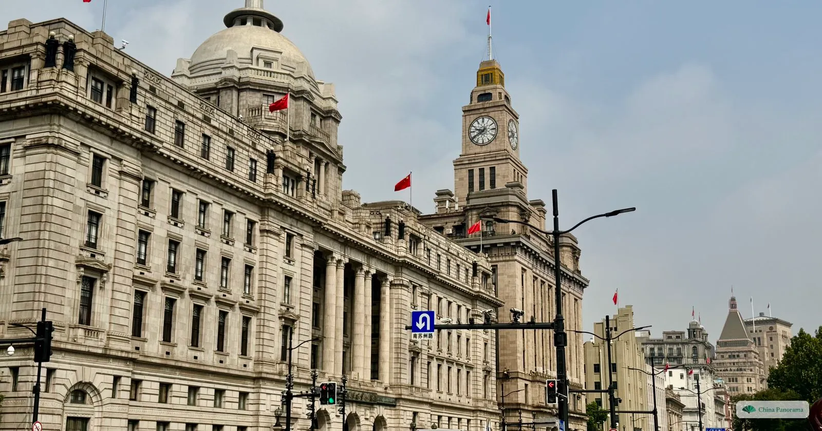 The domed HSBC Building and the Customs House clock tower on the Bund in daylight, with a bus on the road in front