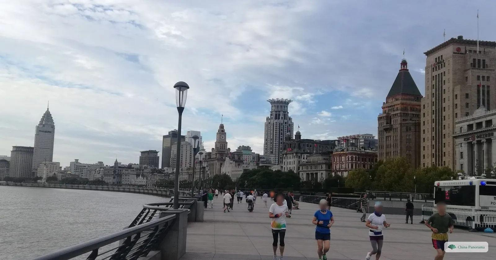 Joggers on the Bund promenade early in the morning, with the old waterfront buildings behind