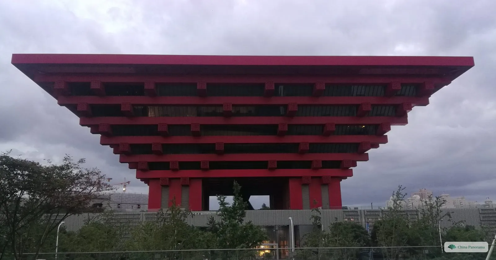 The crimson, upside-down pyramid of the former China Pavilion against a grey evening sky