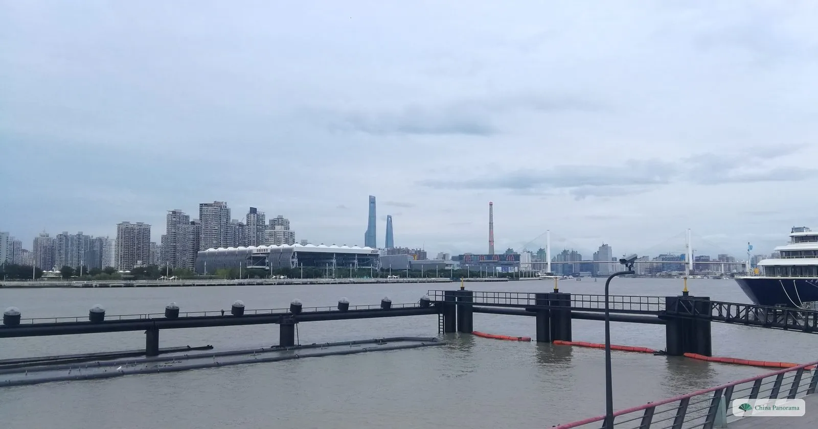The wide Huangpu from the Pudong bank near the Expo site, with a pier and a distant skyline