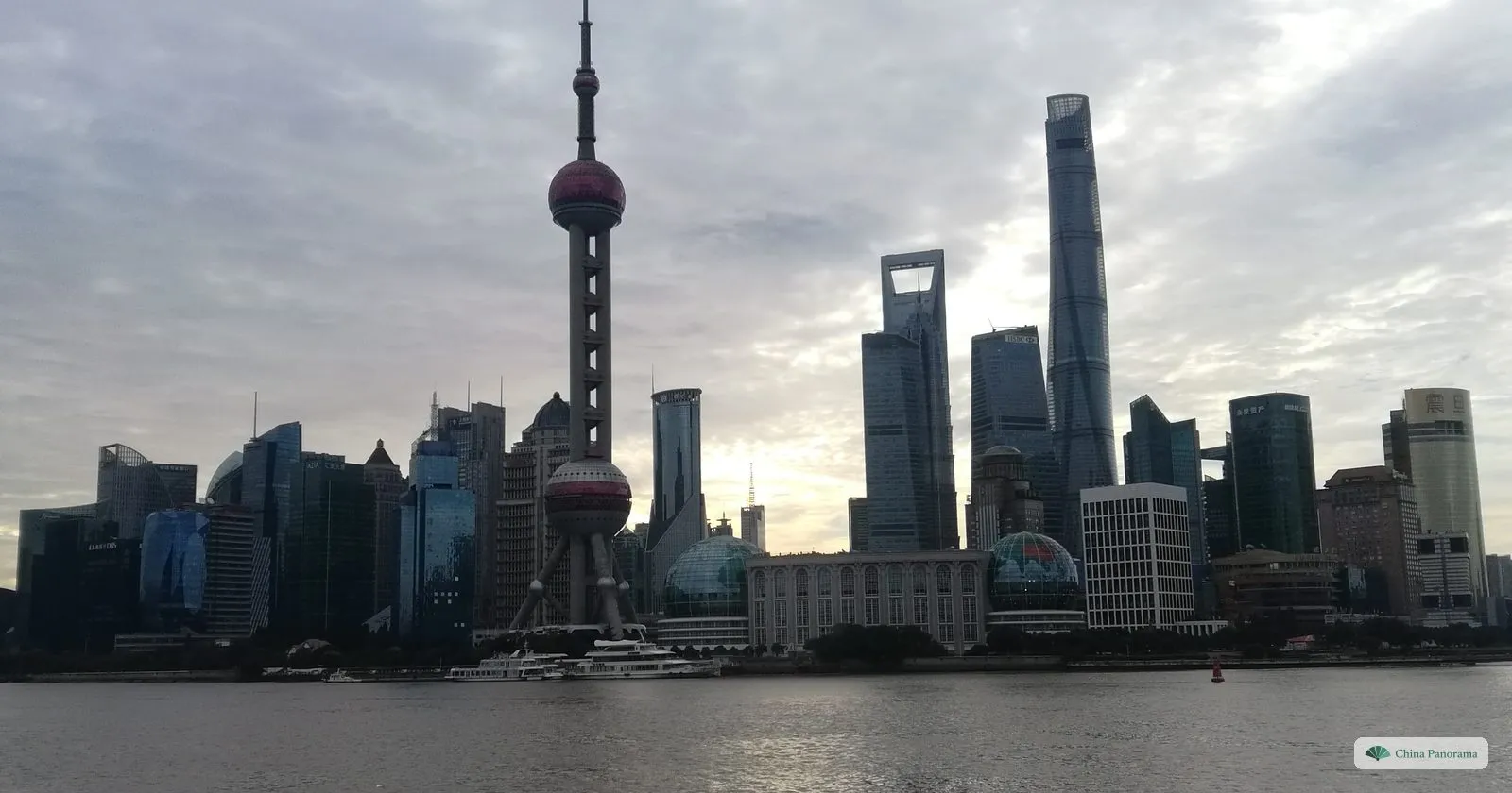 The Lujiazui skyline as a grey silhouette at dawn across the Huangpu, with the Oriental Pearl Tower, the World Financial Center and the Shanghai Tower