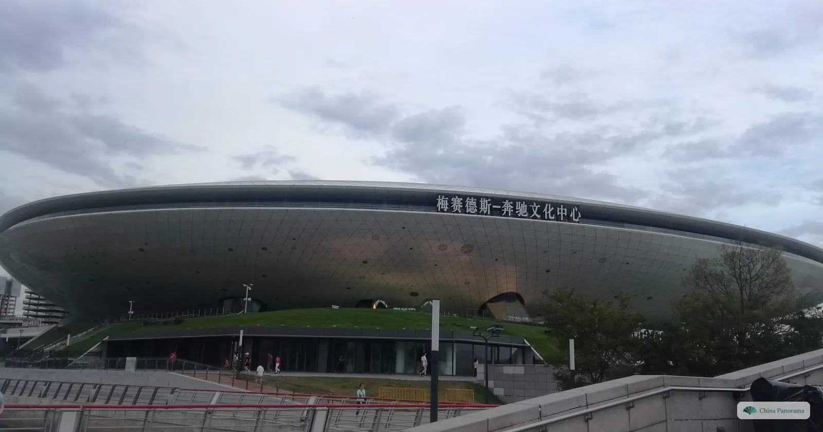 The silver, flying-saucer-shaped Mercedes-Benz Arena on the Expo site, with a green bank in front