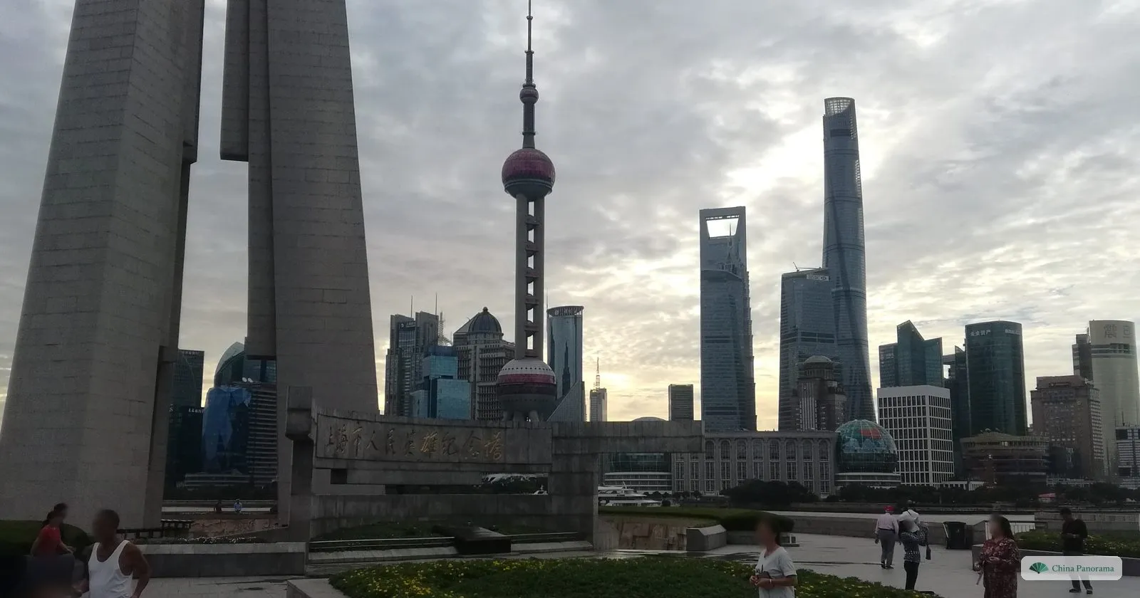 The granite pillars of the Monument to the People’s Heroes in Huangpu Park, with an inscription on the wall and the Oriental Pearl Tower and Shanghai Tower across the river