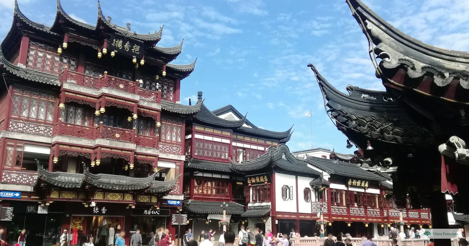 Tiered red-and-black buildings with upturned eaves in the Yuyuan bazaar, with shoppers on the square in front