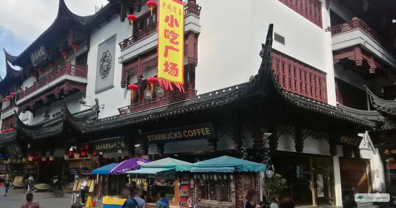 The front of the Yuyuan snack hall under a curved tiled roof, with a Starbucks Coffee sign, a yellow banner and market umbrellas