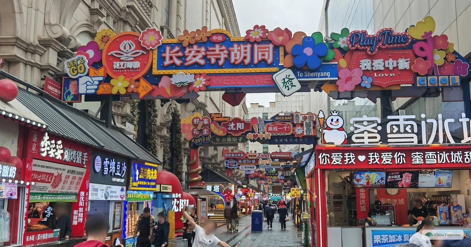 The Chang’ansi Hutong food lane in Shenyang under a gantry of colourful signs, with snack stalls on both sides