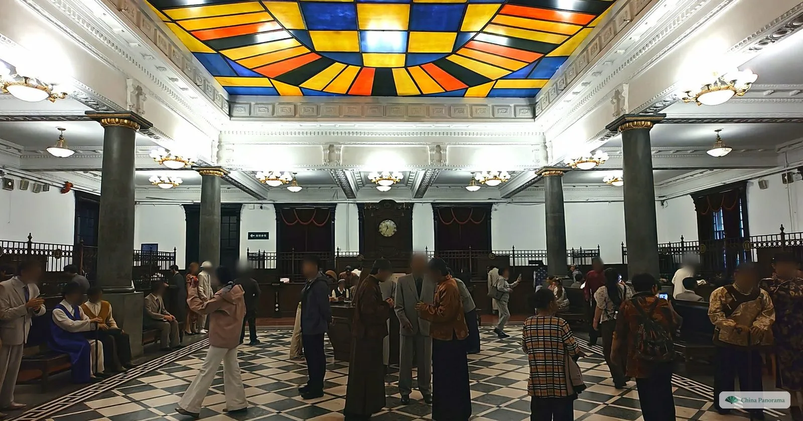 The restored banking hall of the Frontier Bank, with a stained-glass ceiling, a checkerboard floor and wax figures in period dress among visitors