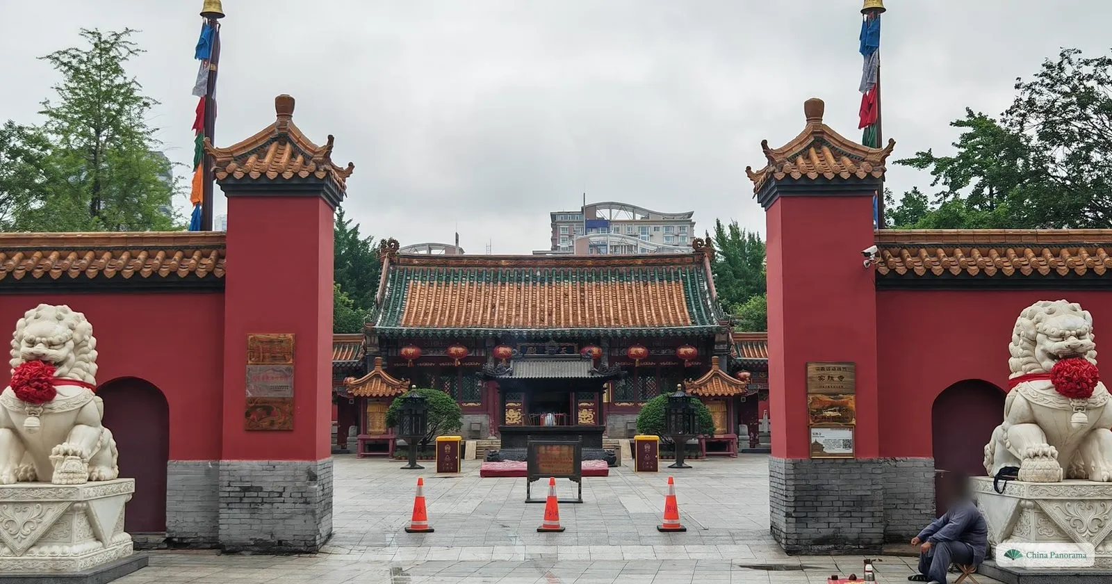 The gate of Huangsi Temple in Shenyang between red walls and two white stone lions, with the main hall behind