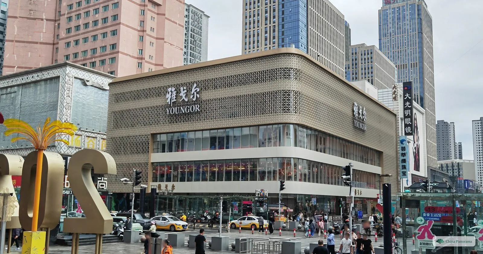 A crossing on Taiyuan Street in Shenyang in front of a large department store, with taxis and pedestrians