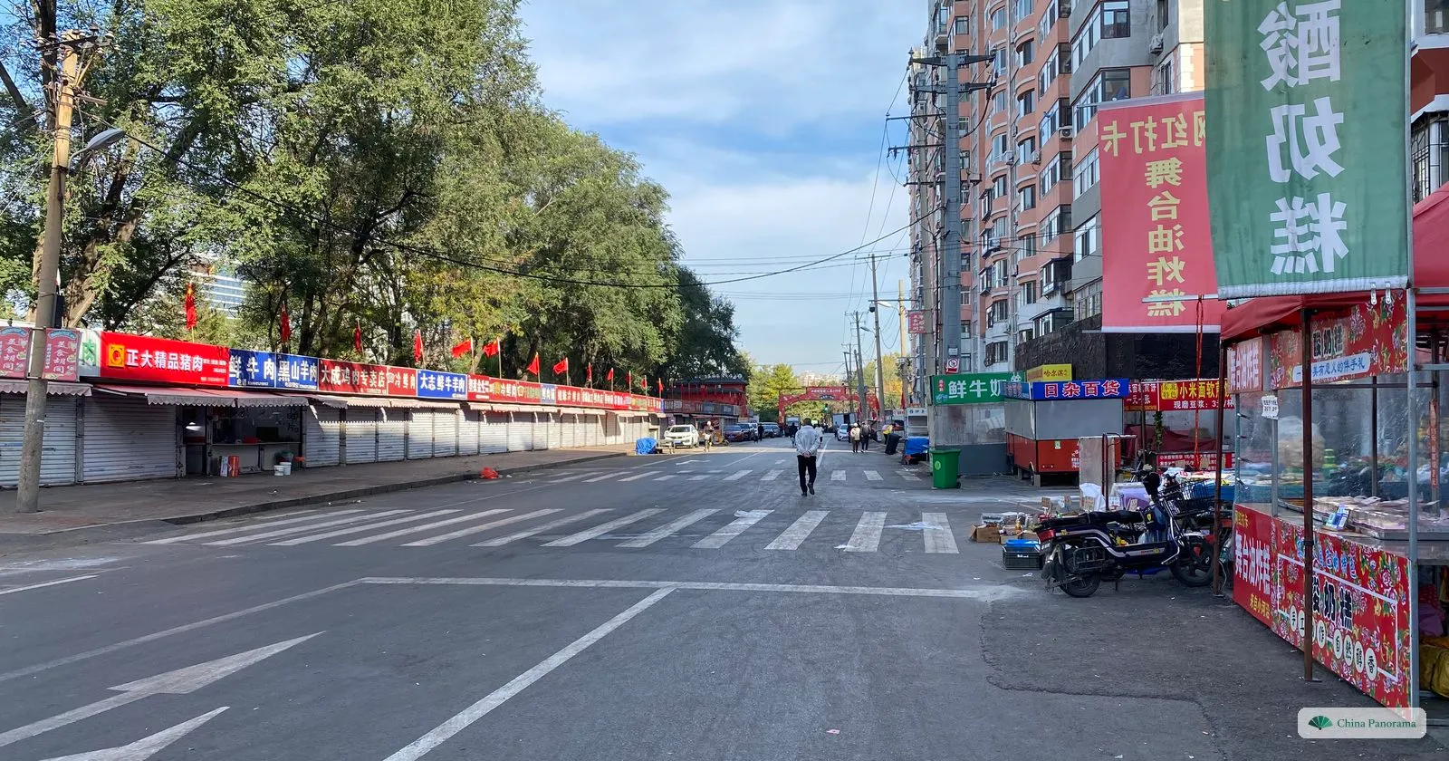 The street of the Xiaoheyan morning market after closing, with shutters down and a stall under a large banner for yoghurt cake