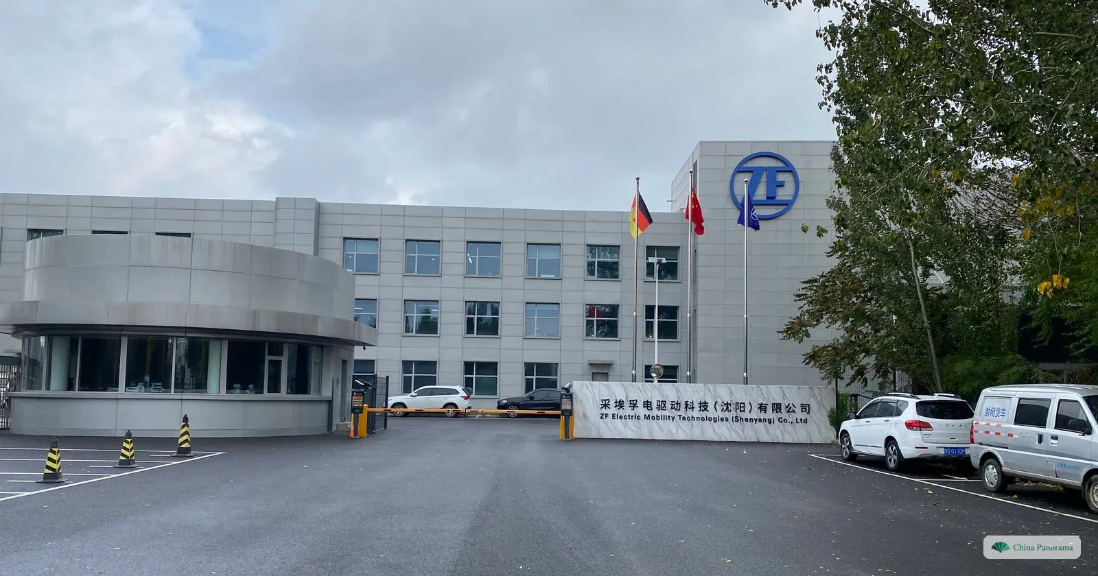 The gate of ZF Electric Mobility Technologies (Shenyang), with the ZF logo on the building, German and Chinese flags and a bilingual company sign