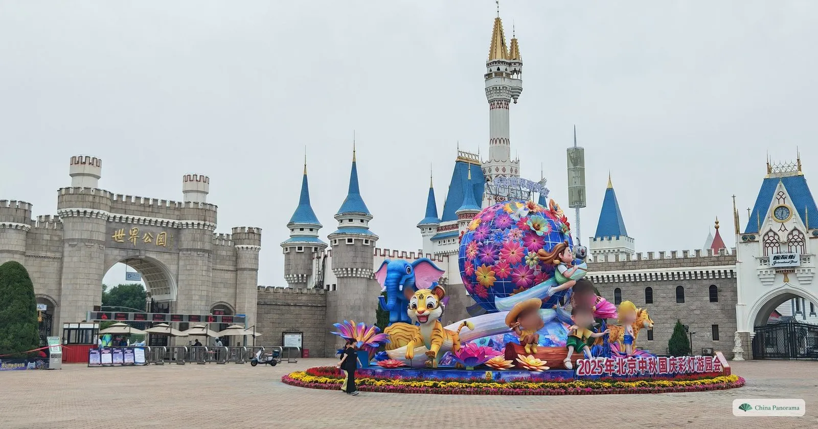 The castle-like entrance of Beijing World Park with turrets and blue spires, and a large flower and lantern display on the forecourt
