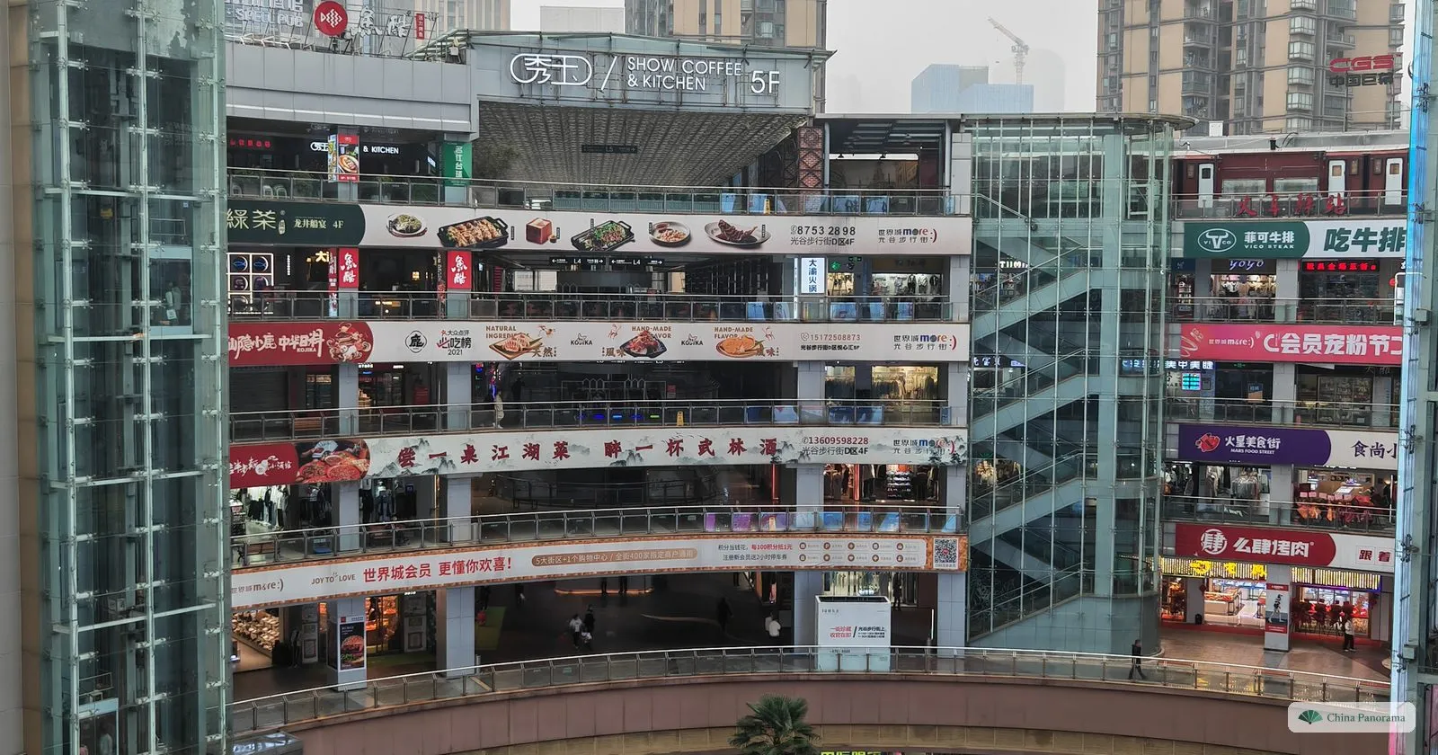 An open court surrounded by five floors of restaurants with glass lifts and long banners