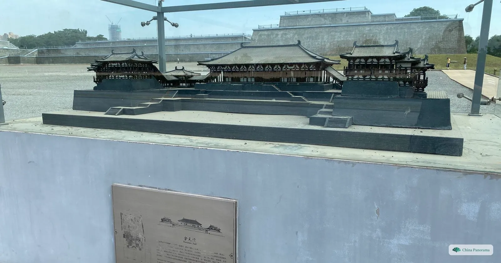 A dark bronze model of Hanyuan Hall with its two side pavilions under a glass canopy, and the stepped brick terrace of the real hall behind it