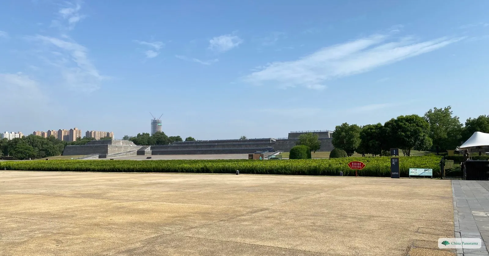A wide, empty parade ground at Daming Palace with the long, low terrace of Hanyuan Hall on the far side and city towers on the horizon